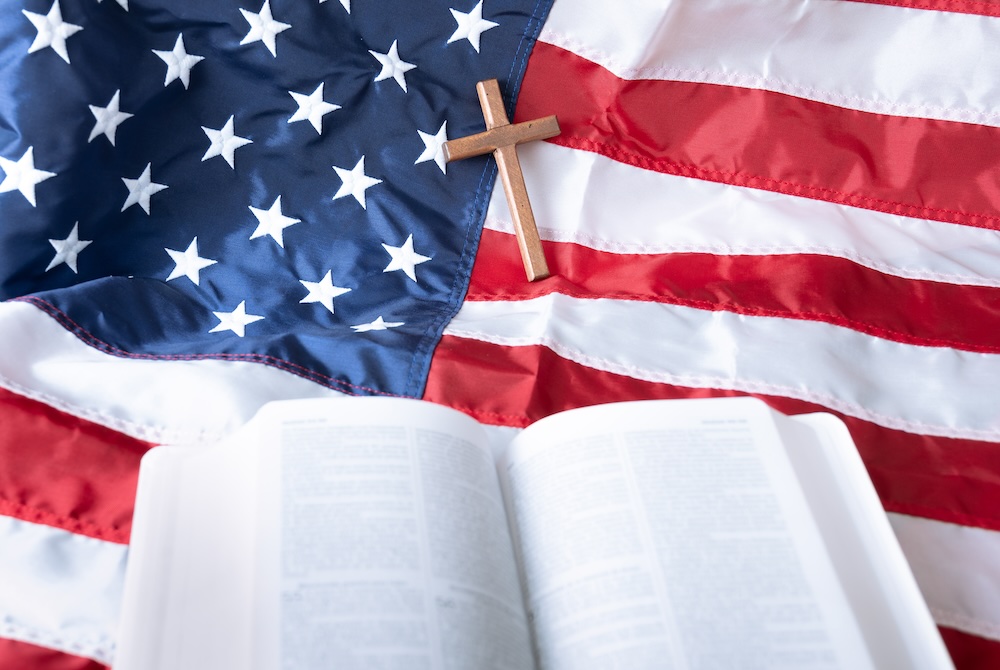 Open Holy bible and Wooden cross over American flag background. selective focus, Copy space.